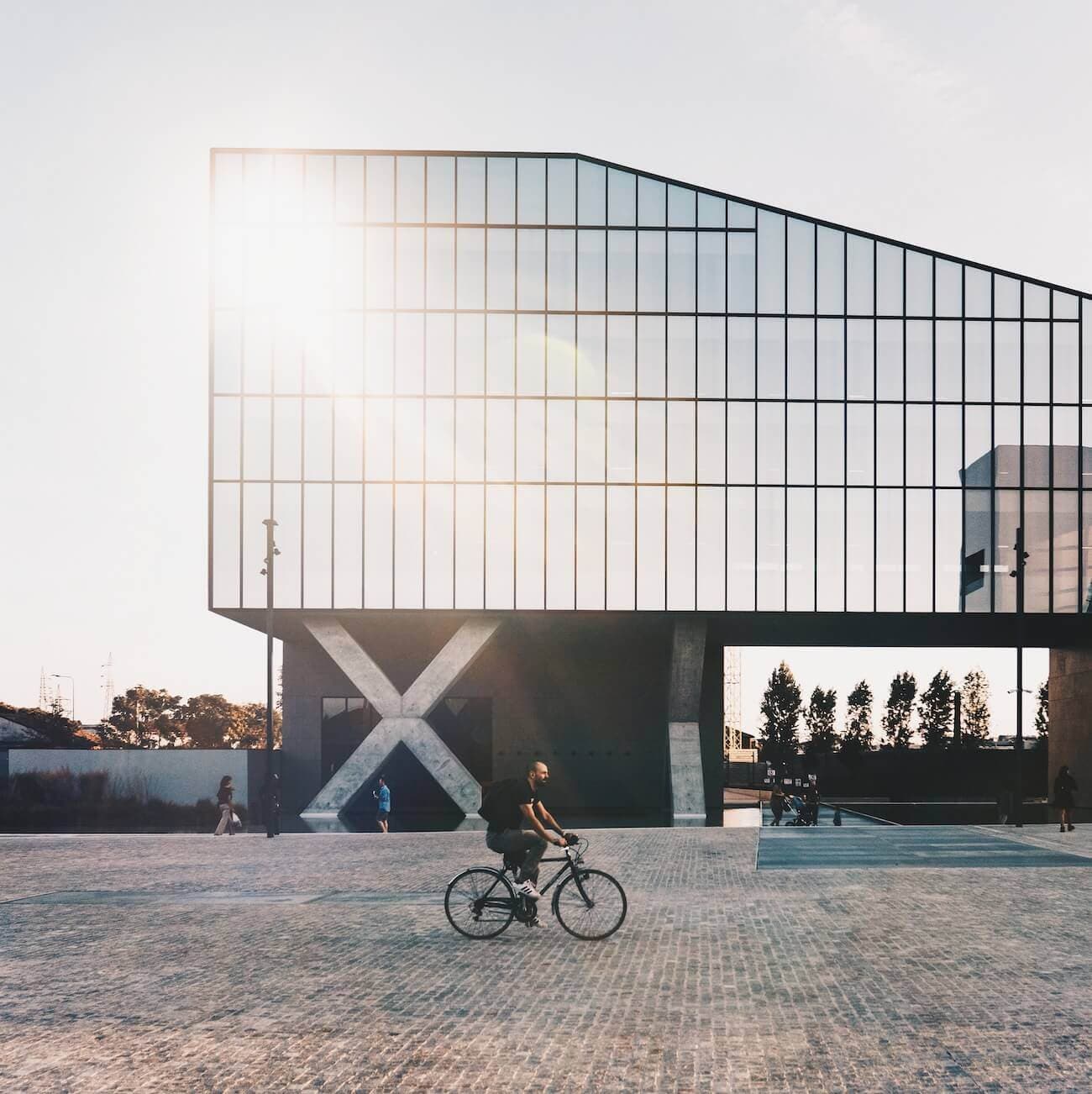 Uomo in bicicletta davanti a un edificio moderno. picture