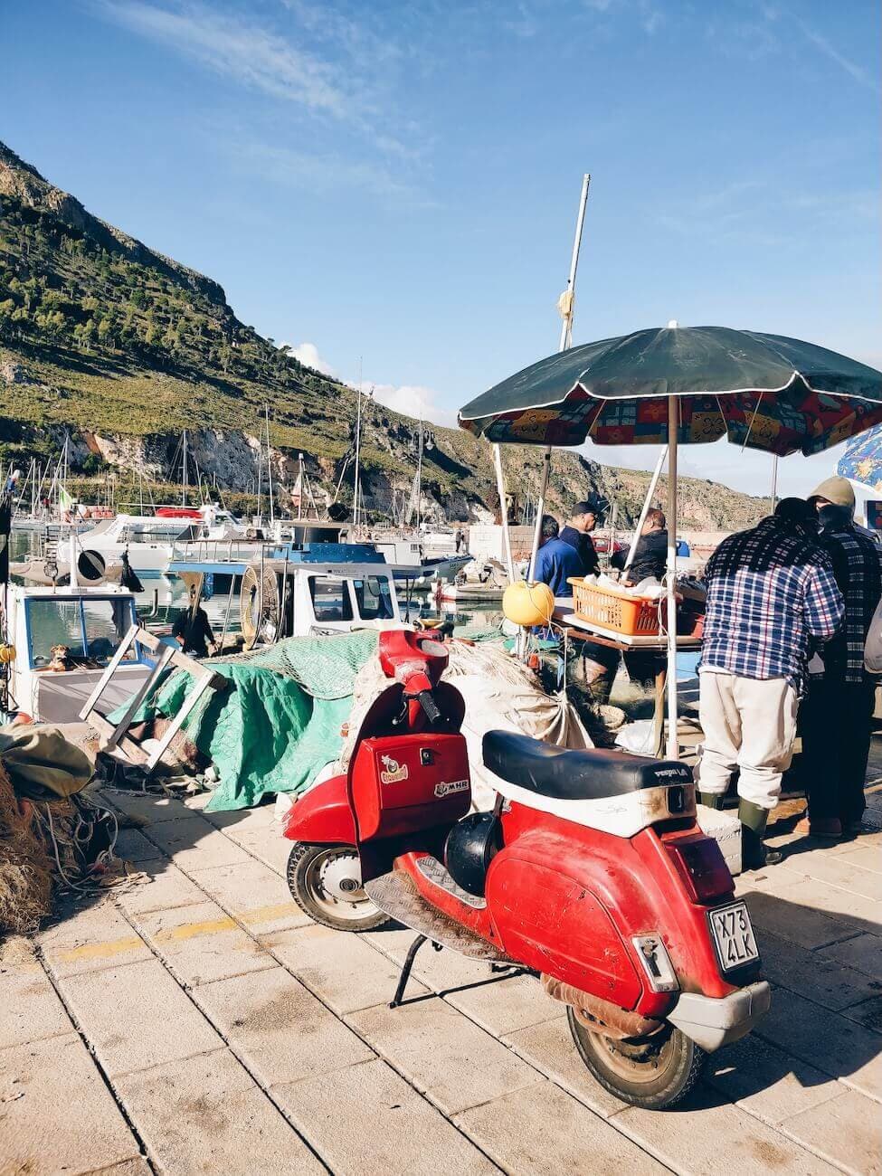 Vespa rossa parcheggiata in un porto di pescherecci. picture